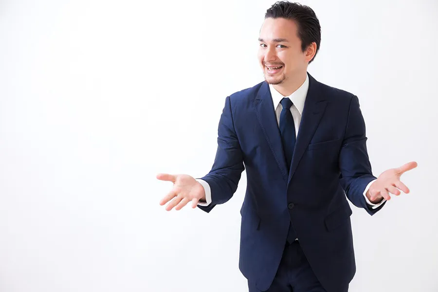 両手を広げるスーツの男性