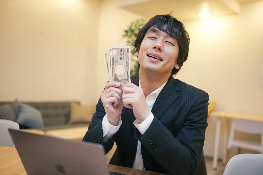 お札を握りしめ笑顔になる男性
